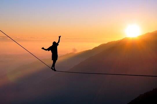 Person walking a tightrope at sunset - representing the balance needed in stakeholder communication